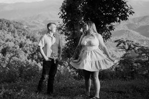 A couple poses together in a scenic mountain landscape during a golden hour photo session.