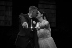 A black and white photograph capturing a tender moment between newlyweds.
