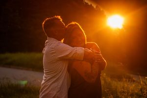 Silhouetted couple embraces in warm golden sunset light creating romantic atmosphere.