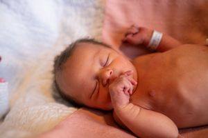 Newborn baby sleeping peacefully on soft blanket in warm lighting.