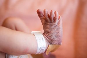 Medical professional applying bandage or medical tape to infant's arm in hospital setting.