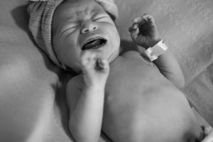 Black and white photo series showing a baby's different facial expressions while lying down.