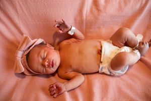 Close-up of newborn baby receiving medical care on pink hospital blanket.