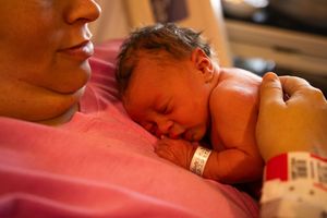 Peaceful sleeping newborn on pink and purple bedding.