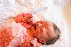 Newborn baby resting on white hospital bedding during medical examination.