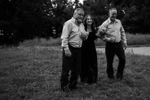 Black and white photo showing people walking together through a grassy field on a casual outdoor stroll.