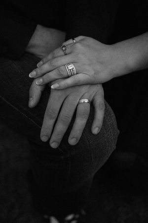 A black and white photo series showing close-up shots of hands with engagement rings against dark backgrounds.