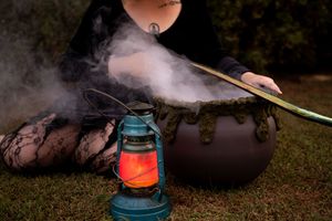 A vintage blue kerosene lantern glows warmly against a dark outdoor background with smoke wisps in the air.