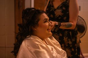 A wedding party shares joyful candid moments together in a light-filled indoor venue.
