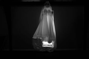 Ghostly white fabric appears to float in darkness creating an ethereal and haunting atmosphere.