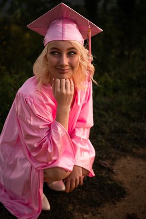 A graduate in pink cap and gown poses outdoors in a series of candid shots.
