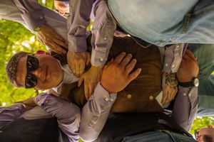 Hands stacked together in a team huddle gesture wearing formal attire.