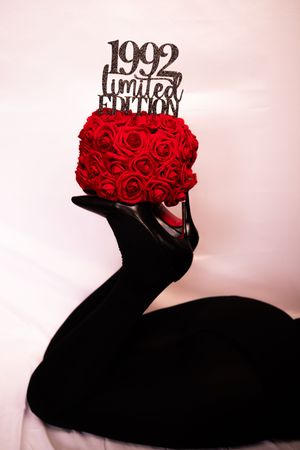 A silhouette of hands holding up bright red roses against a light pink background in a creative photo series.
