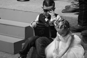 A vintage black and white photo of children sitting on steps, with one in formal wear and one in a dress.