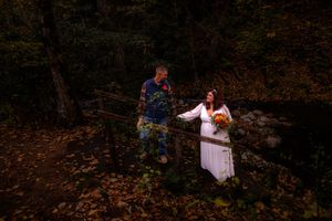 A couple walks through a scenic autumn forest with fallen leaves and warm lighting creating a romantic atmosphere.