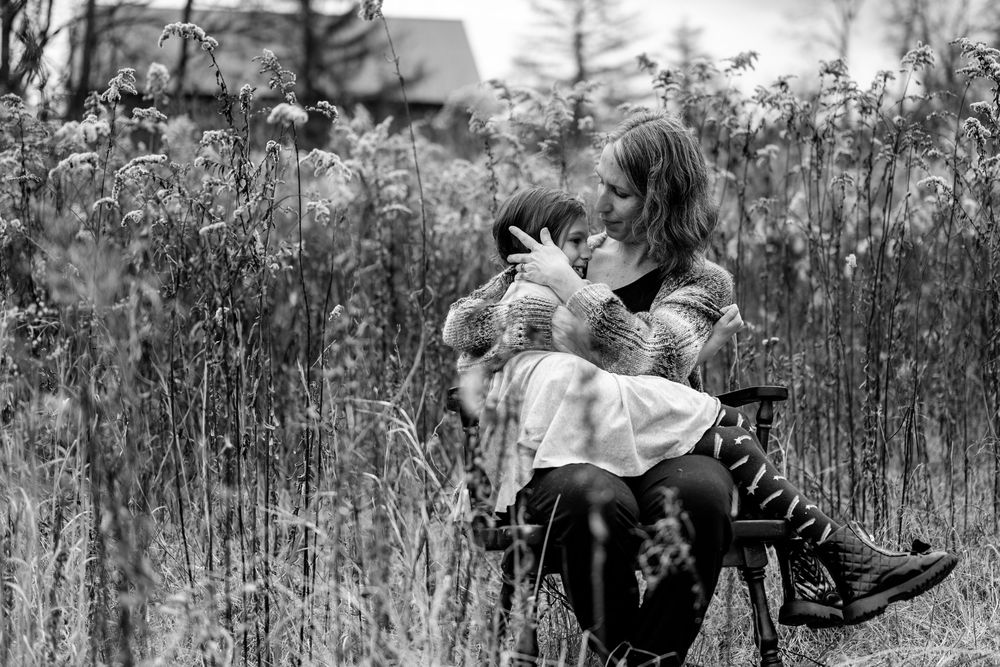 Family enjoying a playful moment together outdoors among tall grass and natural scenery.