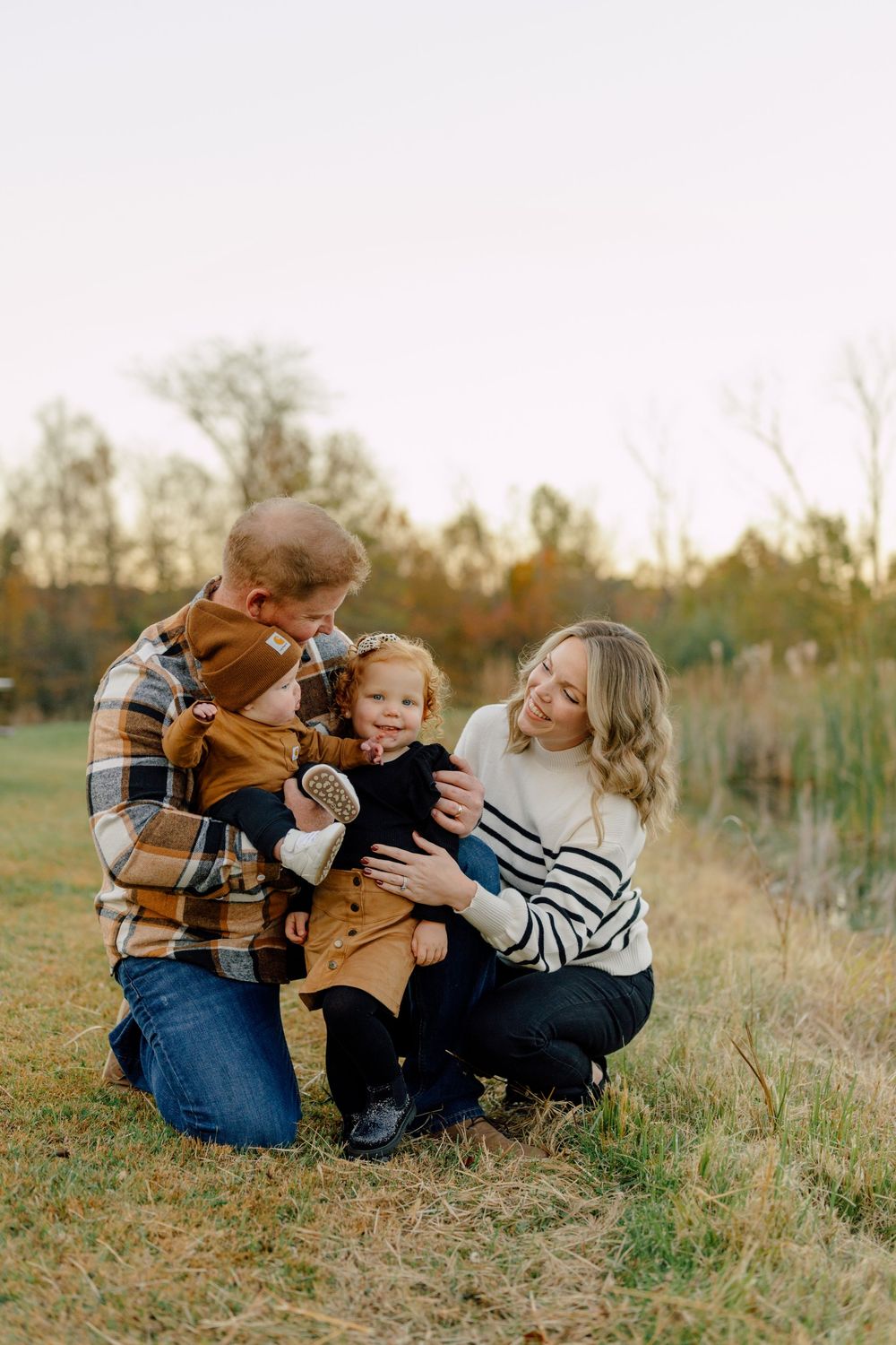 Family playing and laughing together in autumn field at sunset.