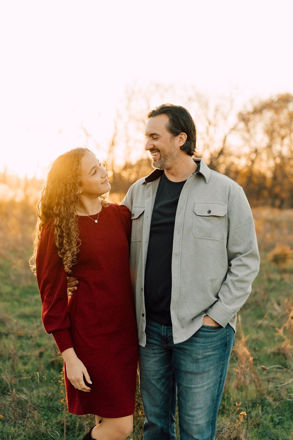 Couple sharing loving glances in a field during golden hour.