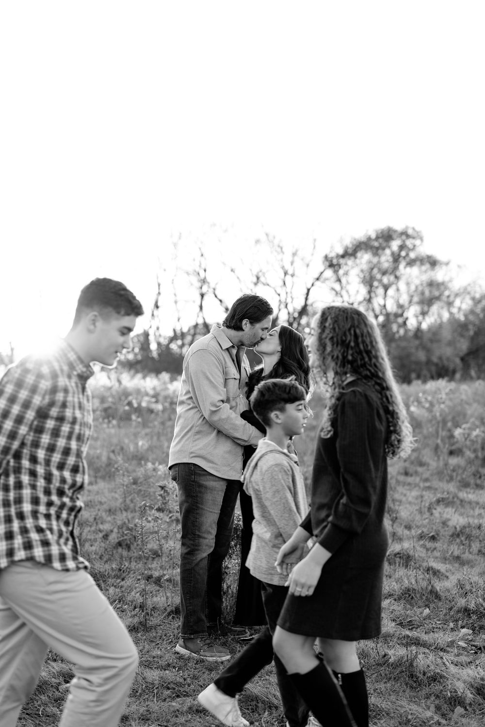 Black and white series of playful family moments in a field.