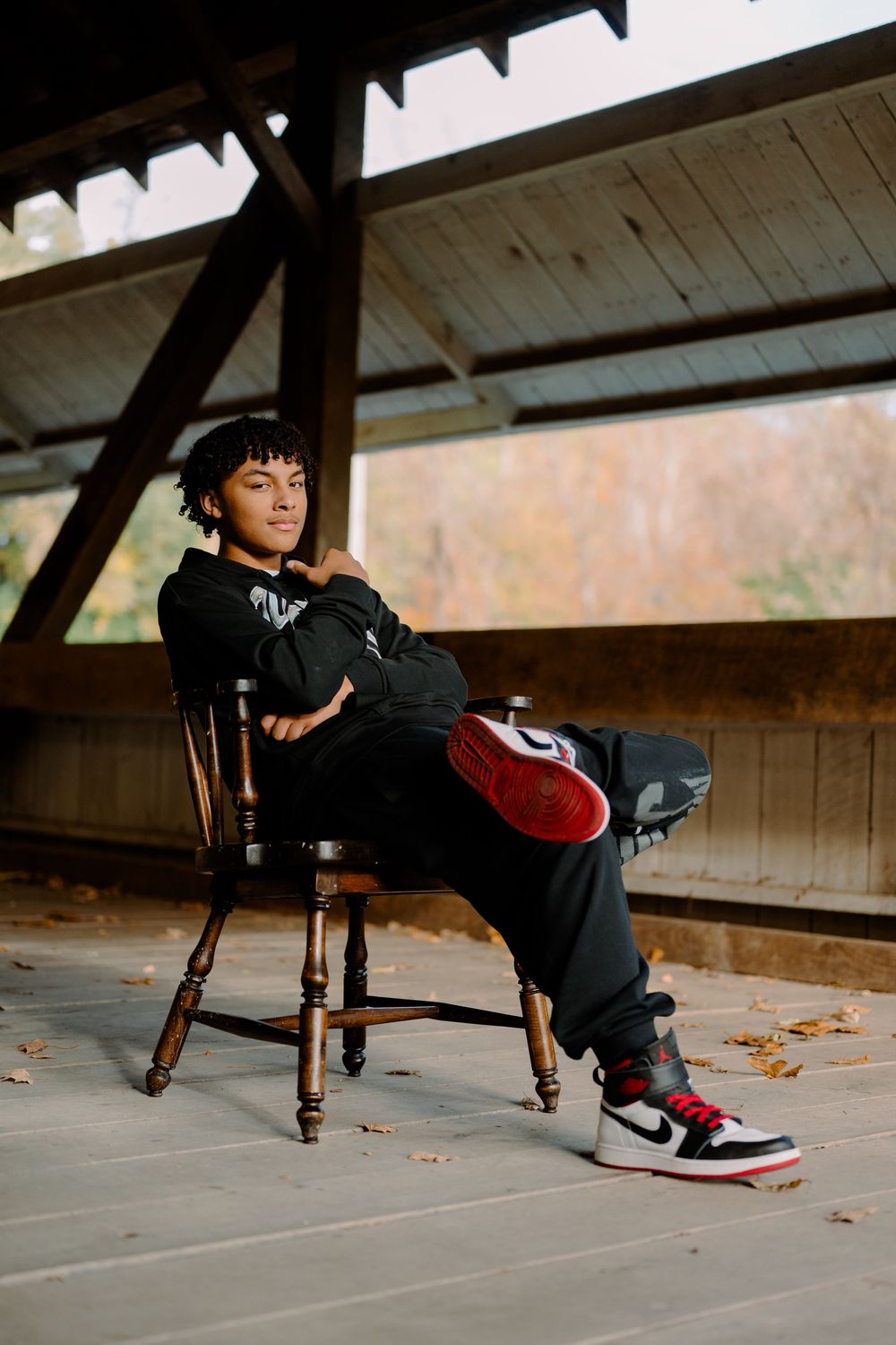 Casual portrait session on a wooden chair showing off trendy sneakers.