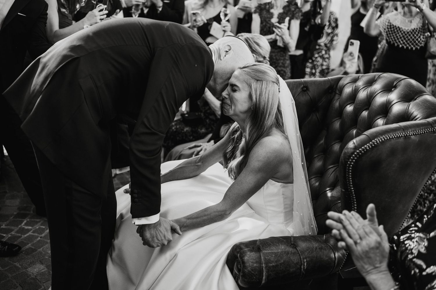 Joyful wedding ceremony moment showing hands grasping bouquet in black and white.