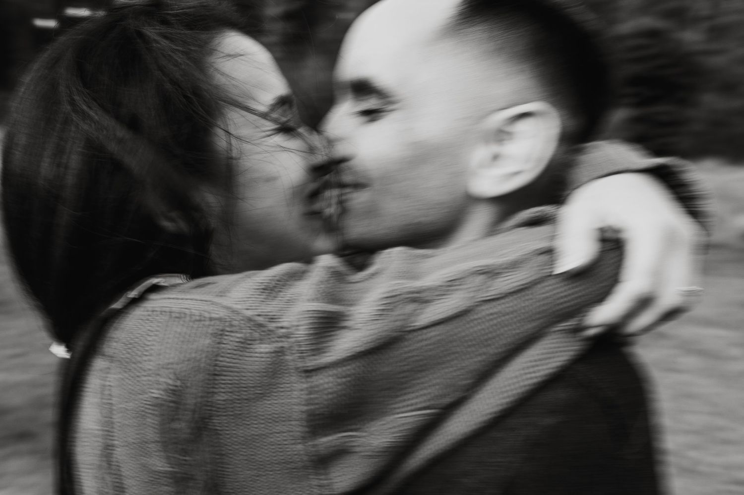 Candid black and white photo of couple laughing and embracing intimately.