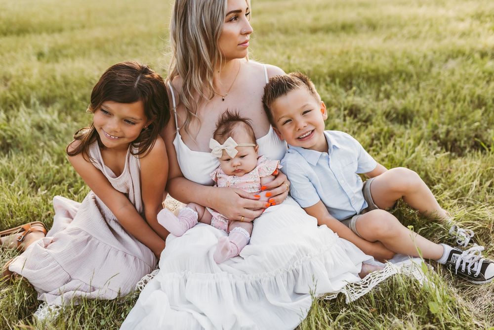 A series of candid family photos taken outdoors on a grassy field in warm sunlight.