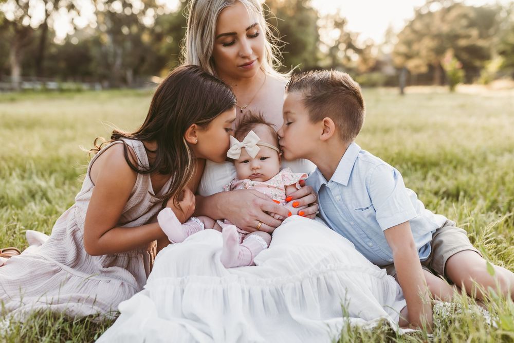 Family sitting together in a sunlit grassy field during golden hour photo session.