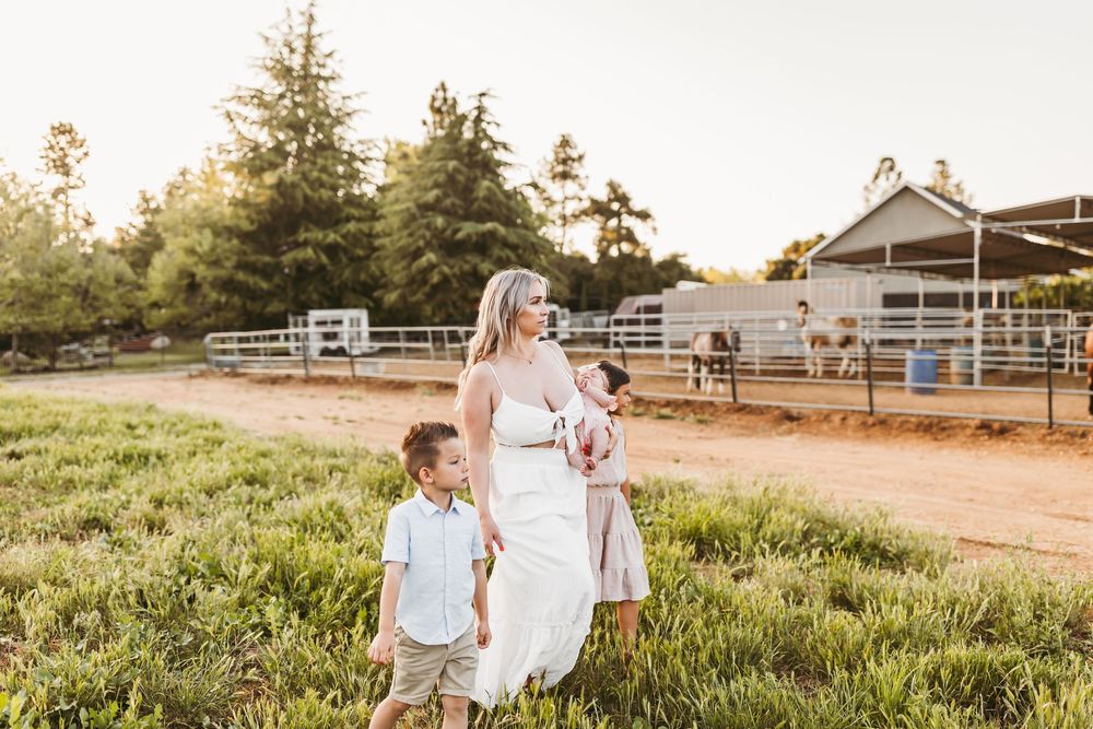Family strolling along rustic fence line at sunset with trees in background.