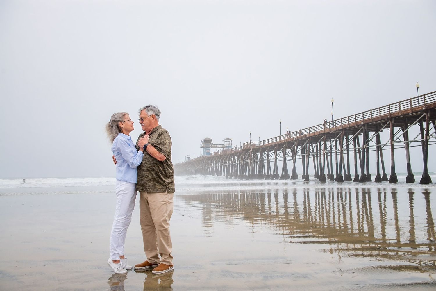 Romantic seaside moment with wooden pier extending into foggy ocean waters.