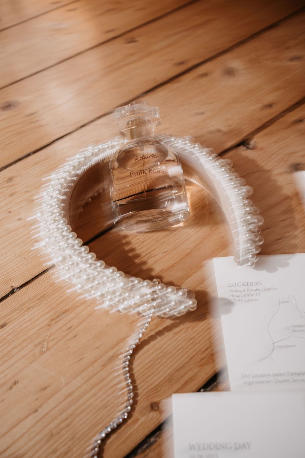 Pearl necklace forms a spiral shape on rustic wooden floorboards with paper notes in soft lighting.