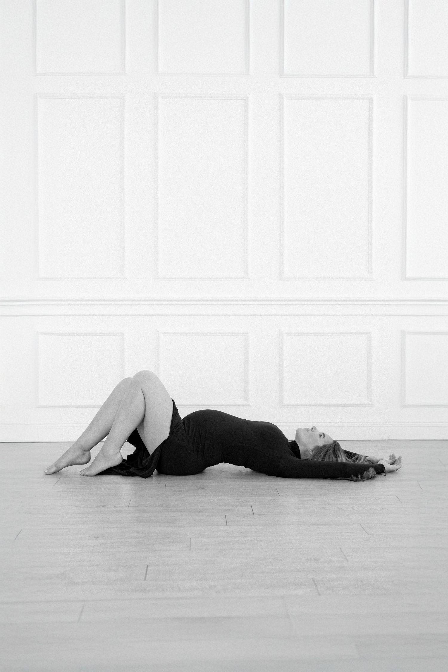 A sequence of four black and white photos showing a figure in dark clothing lying down on a light colored floor.