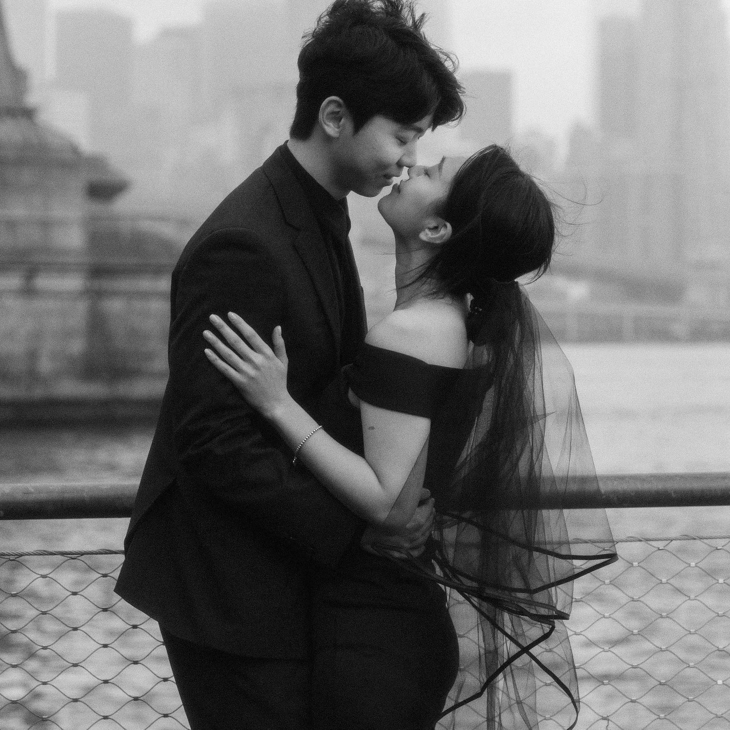 Romantic black and white engagement photos of a couple embracing on a city rooftop.