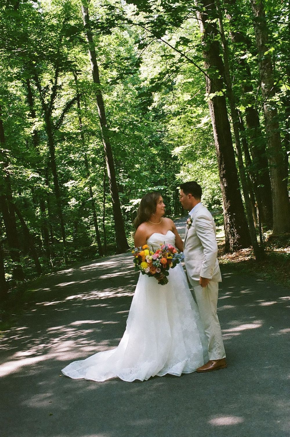 A couple shares a romantic moment on a tree-lined path during their wedding photoshoot.