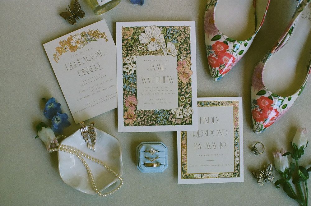 Elegant wedding stationery with floral designs and decorative elements arranged on a light colored surface.