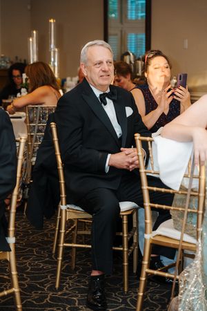 Elegant wedding reception with formal attire and gold chiavari chairs.