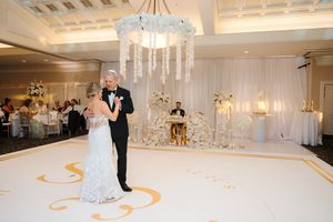 An elegant white ballroom setup with crystal chandeliers and curved decorative elements on the floor.