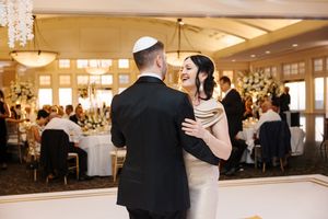 Couples dance together during an elegant wedding reception in a grand ballroom with crystal chandeliers.