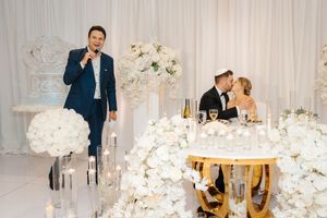 Elegant wedding reception setup with white floral arrangements and romantic candlelit table decor in luxurious ballroom setting.