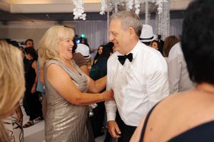 Wedding guests dance and celebrate together on a festive dance floor under crystal chandeliers.