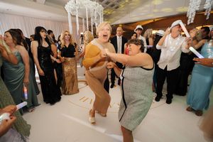 Wedding guests dancing and celebrating together on a dance floor at an elegant reception venue with crystal chandeliers.
