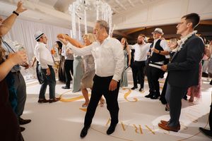 Wedding guests dancing and celebrating together on the dance floor at an elegant indoor reception venue.