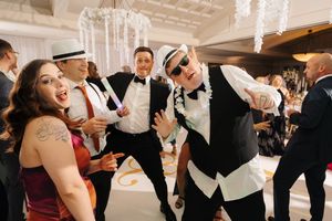 A group of wedding guests dance and celebrate together on a crowded dance floor at a reception party.