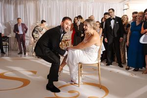 A wedding reception scene shows a traditional garter toss moment with guests watching in an elegant white ballroom.