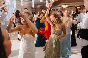 Wedding guests dance and celebrate together on a lively dance floor at an elegant indoor reception venue.