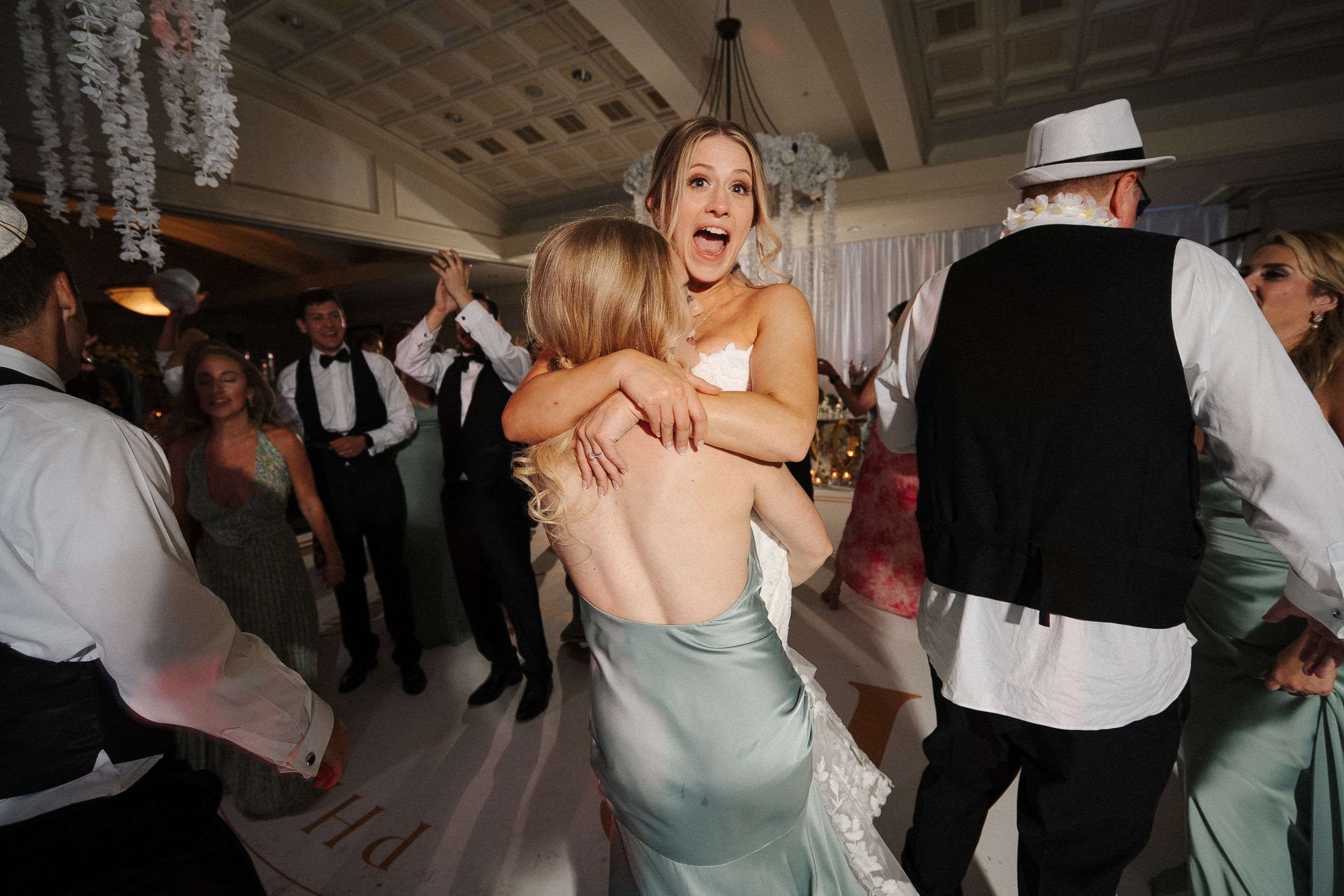 Wedding guests dance and celebrate together on a crowded dance floor at an elegant indoor reception venue.
