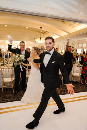 Wedding couple performs dramatic dance moves on a white dance floor at an elegant ballroom reception.