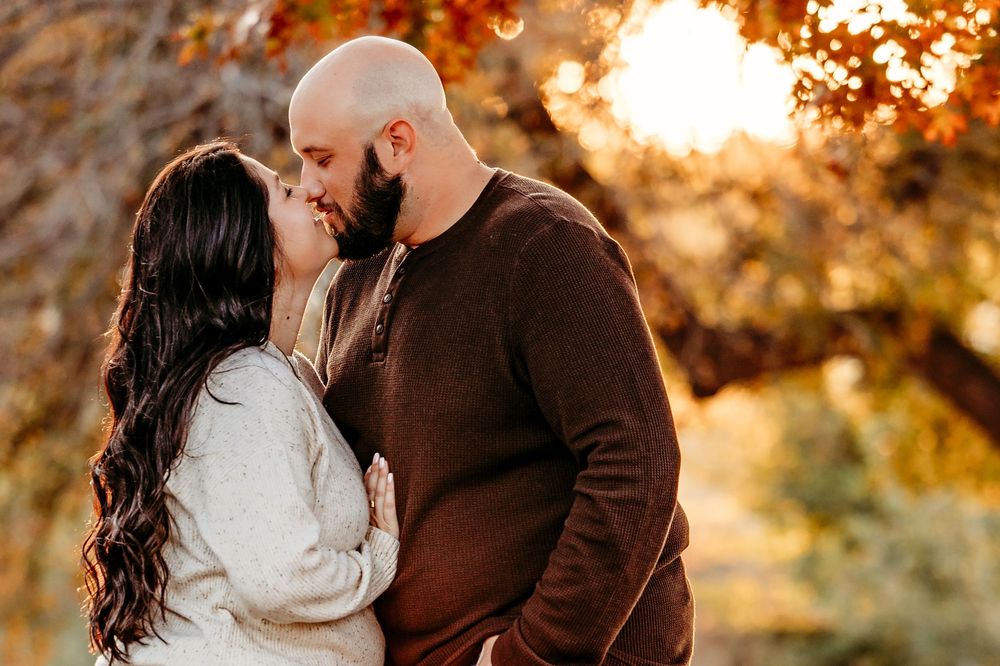 A couple shares a romantic moment during golden hour with autumn foliage in the background in Keller, TX
