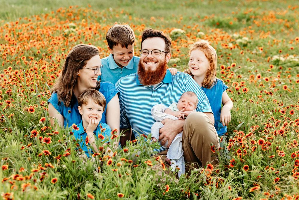 Family enjoys a playful moment together in a vibrant field of orange wildflowers on a sunny day in Fort Worth