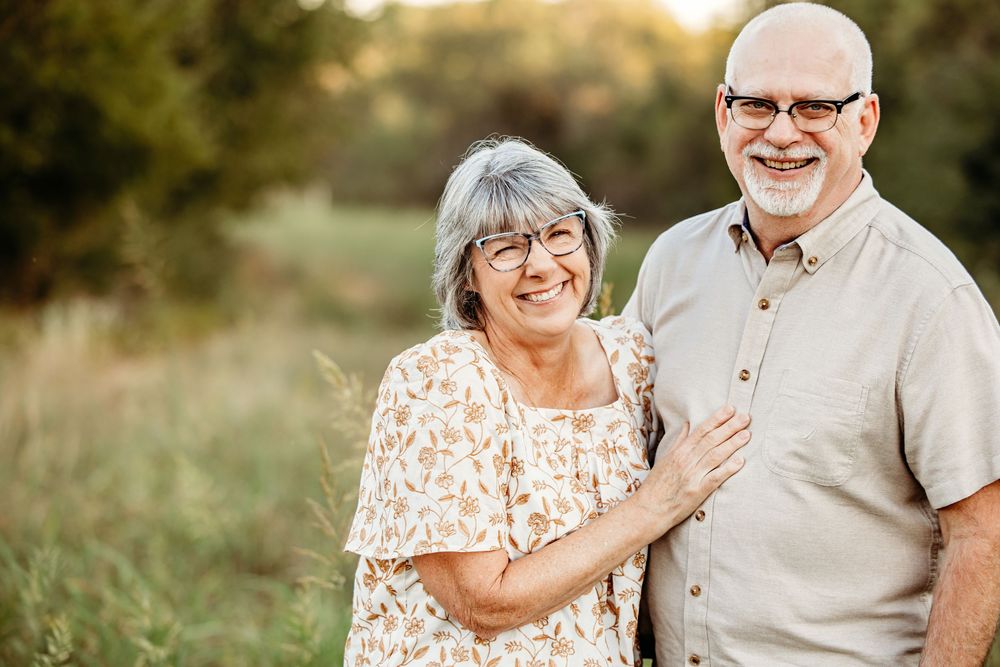A couple shares tender moments in a sunlit field during a golden hour outdoor photo session in Fort Worth